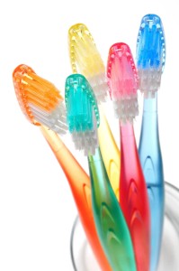 10739398 - five colorful toothbrushes in a water glass on white background