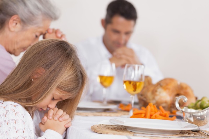 18121559 - little girl saying grace with family before thanksgiving dinner