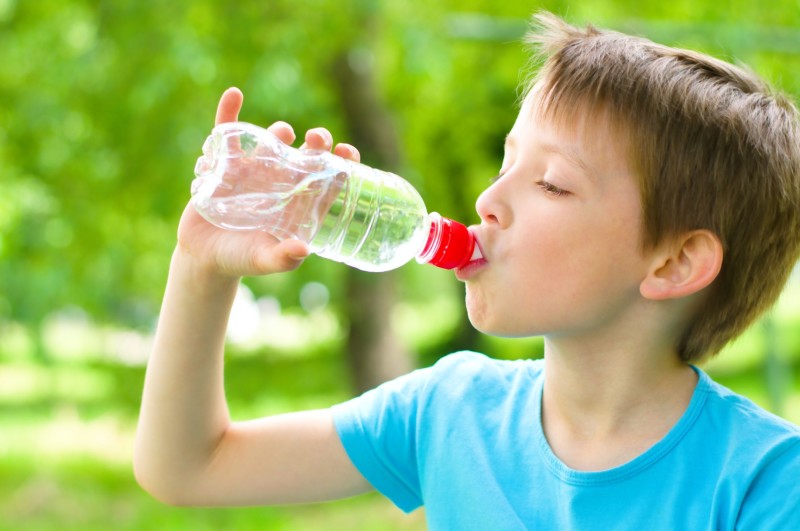 20451288 - boy drinks water from a bottle outdoors