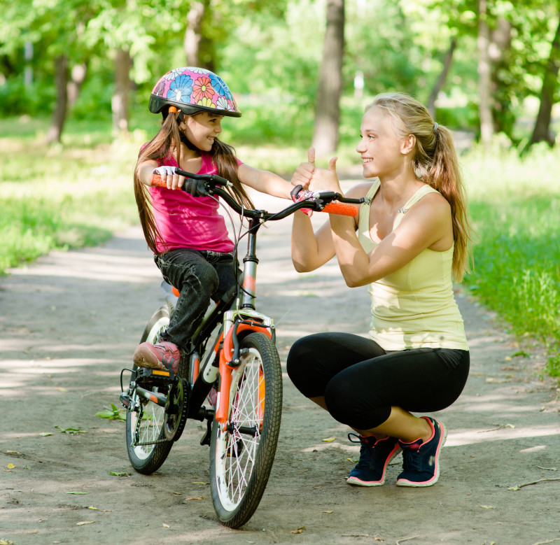 young mother praises her daughter, who learned to ride a bike