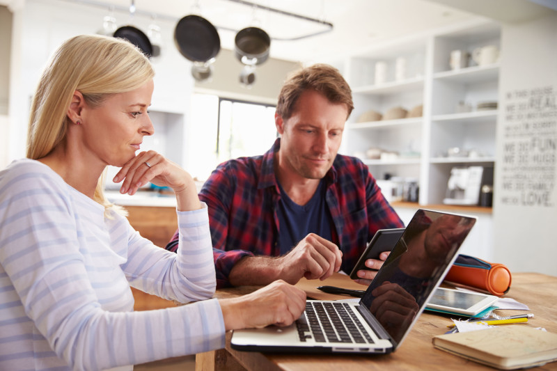 41392705 - stressed couple sitting in their kitchen using computers